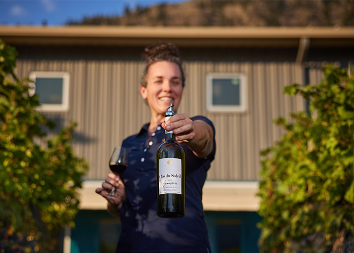 Woman presenting a bottle of Clos du Soleil wine